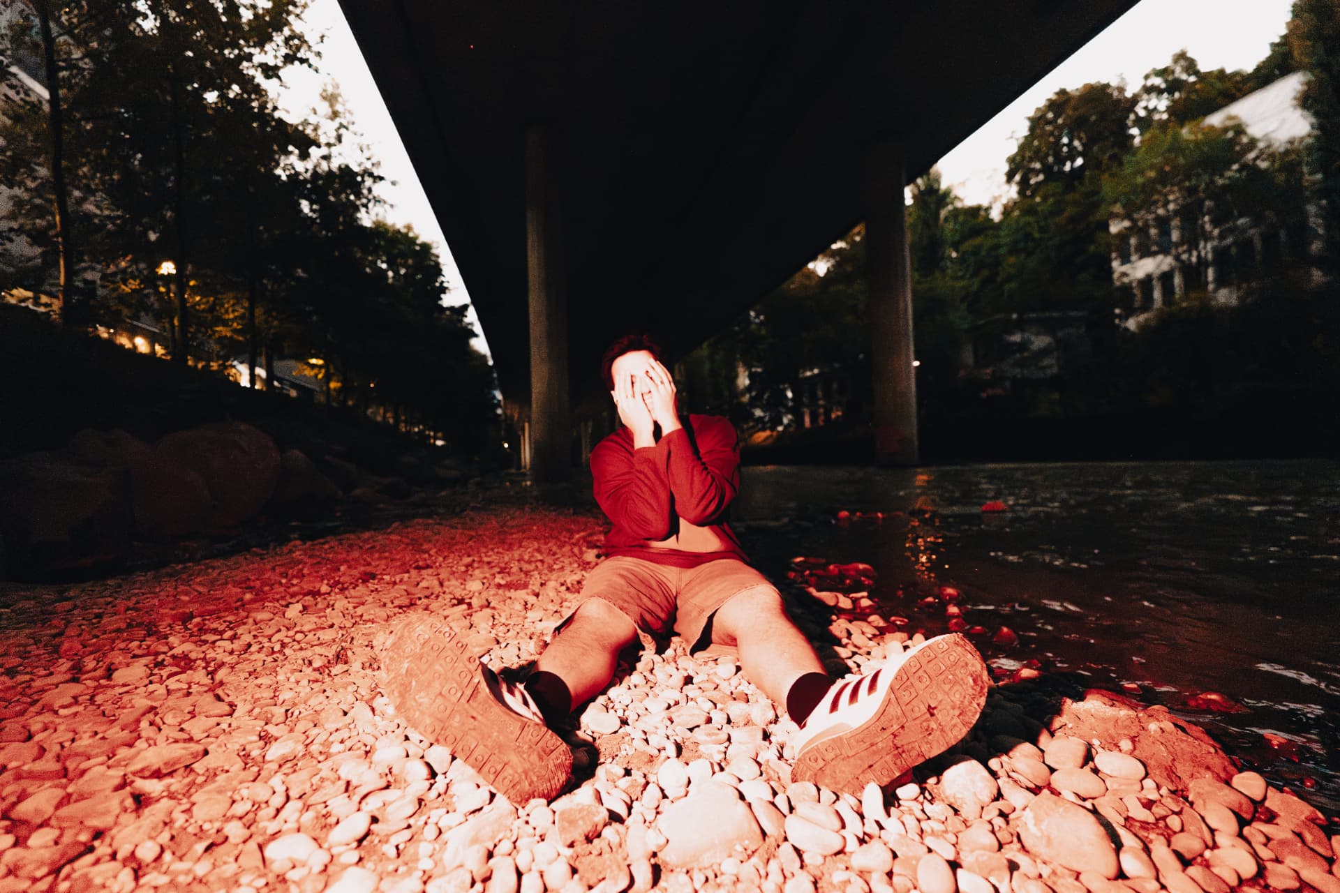Aakash sitting on the riverbank under a bridge